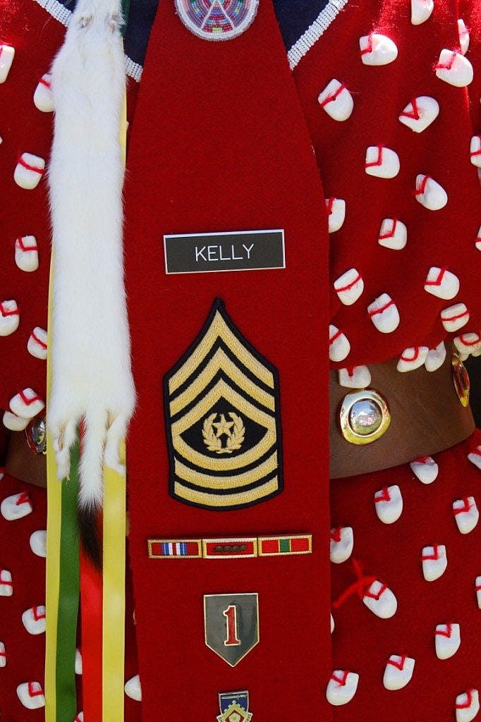 The Apsaaloooke Nation Color Guard's female veteran incorporates military regalia with traditional dress.