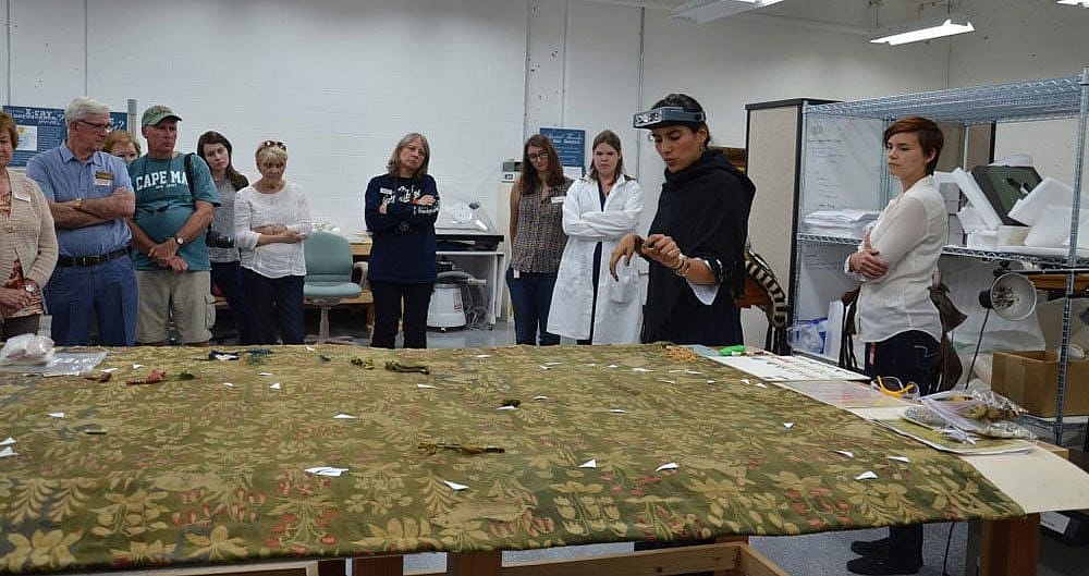Vanessa is explaining to a group of museum visitors some of the past conservation treatments done on the tapestry and the treatments she has planned.