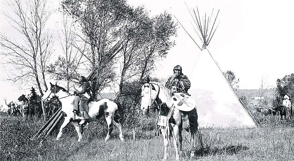 Joseph Henry Sharp (1859-1953), "Crow Indians on Horses in Tipi Village." Black and white photograph.