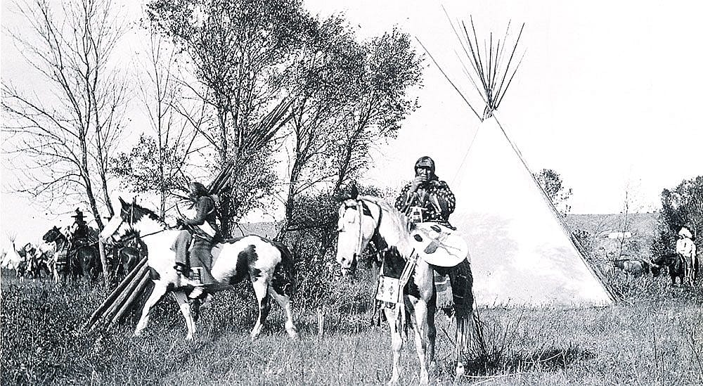 Joseph Henry Sharp (1859-1953), "Crow Indians on Horses in Tipi Village." Black and white photograph.