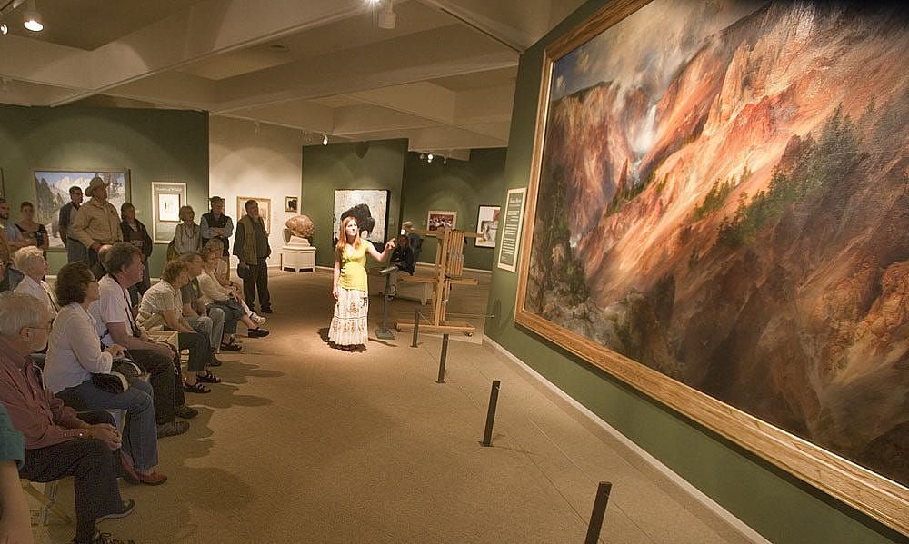 Engaged audience attending a spotlight presentation on a majestic Moran painting, previously on loan and now housed at the Smithsonian American Art Museum.