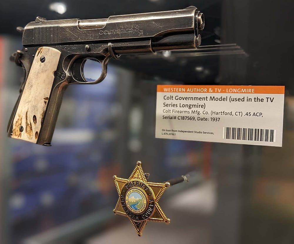 Longmire show props (gun and badge) displayed in the Cody Firearms Museum.