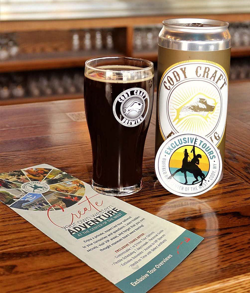 Cody Craft Brewing tumbler and can resting on a bar with an Exclusive Tours brochure.
