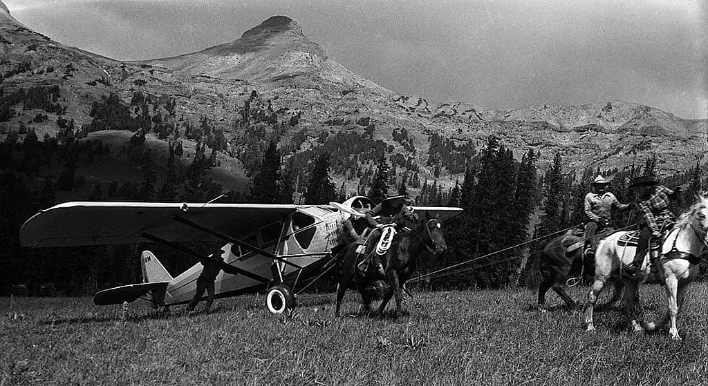 Lucille Nichols, on her father's white horse, leads riders tugging on Bill Monday's plane. MS3 Charles Belden Collection. PN.67.838b