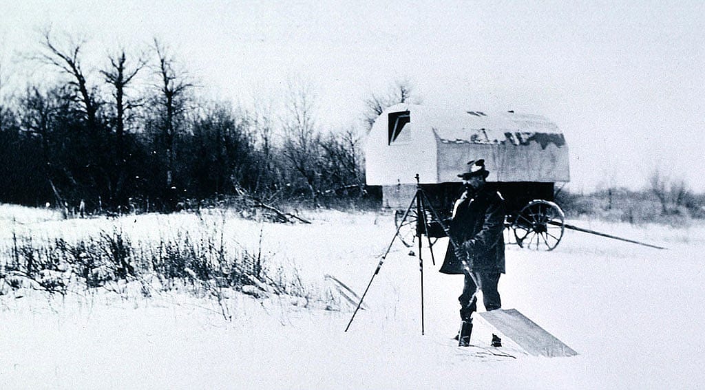 Sharp sets up an easel to paint the winter landscape, ca. 1905. On the Crow Agency, Sharp used an old sheepherder's wagon as a mobile painting studio. P.22.42