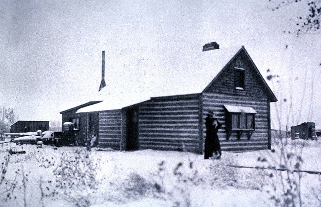 Absarokee Hut in winter, ca. 1905. Addie Sharp stands on the front walk, holding her dog Frans Hals. P. 22.523