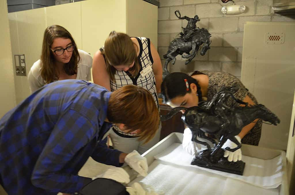 Conservation interns examine a Proctor Sculpture in storage. "Pursued" #11.75