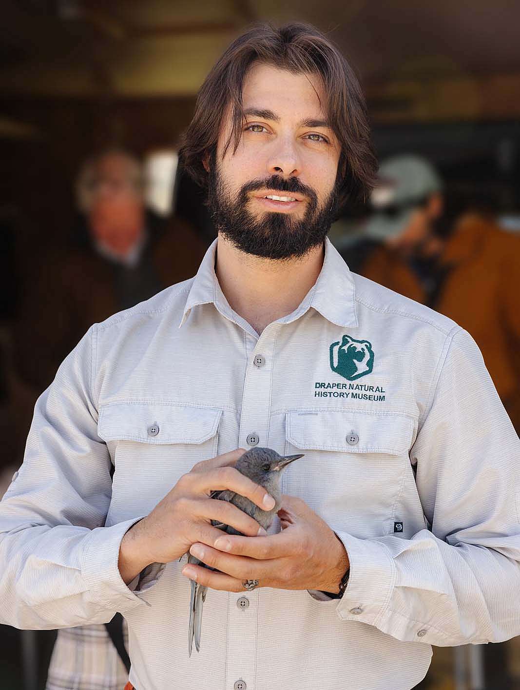 Corey Anco in the field, holding a pinyon jay.