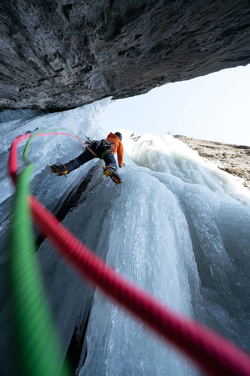 Red and green climbing ropes hang down from Dane Steadman as he climbs Too Cold to Fire, a frozen waterfall in Cody's South Fork Valley. Aaron Mulkey photo.