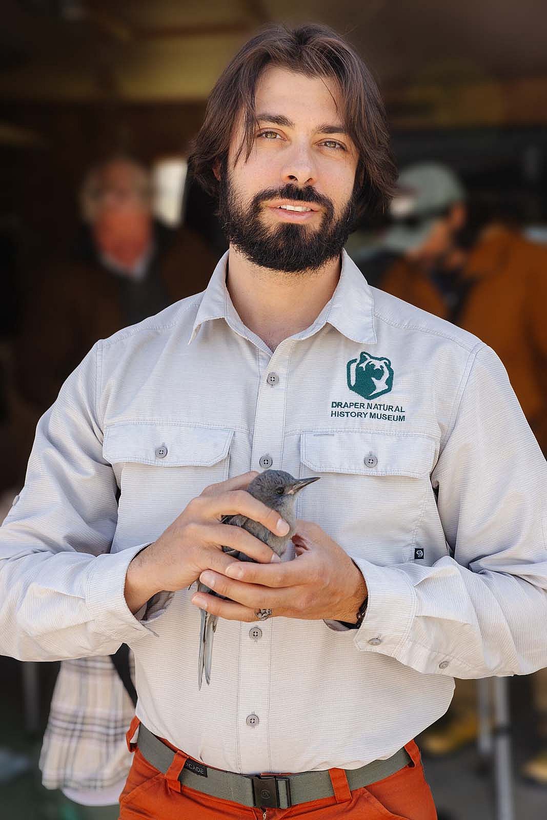 Corey Anco in the field, holding a pinyon jay.