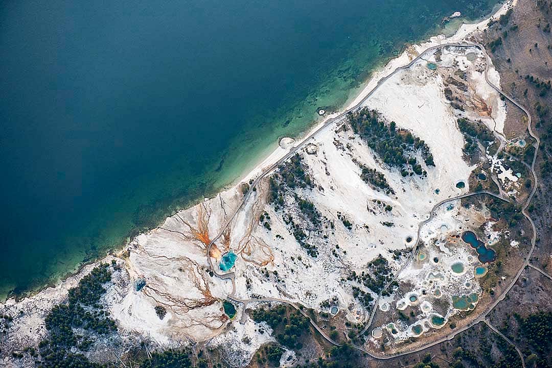 "West Thumb." Visitors marvel at the colorful pools and bubbling springs along the shore of Yellowstone Lake at West Thumb geyser basin. The pools they are looking at are just a small part of a larger-scale hydrothermal system that extends across the entire northern half of the lake. Aerial support provided by LightHawk. What Lies Beneath: Exploring Yellowstone Lake's Mysterious Vents / Photographs by Chris Linder, Woods Hole Oceanographic Institution.