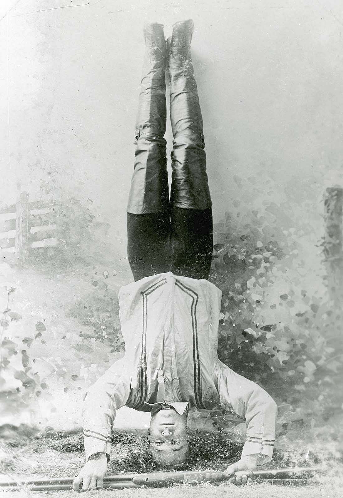 Johnny Baker posing upside down with shotgun. MS 71 Vincent Mercaldo Collection, McCracken Research Library. P.71.34