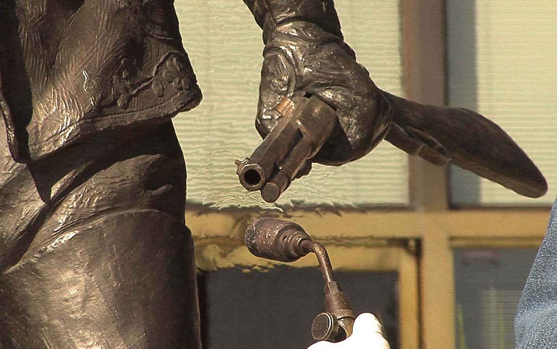Heating rifle barrel on "Plainsman" to reapply shiny coloration. Bob Scriver (1914-1999). "Buffalo BillโPlainsman," 1976. Cast by Modern Art Foundry, N.Y. Bronze, 86.5 x 62 x 50.25 inches. 12.77