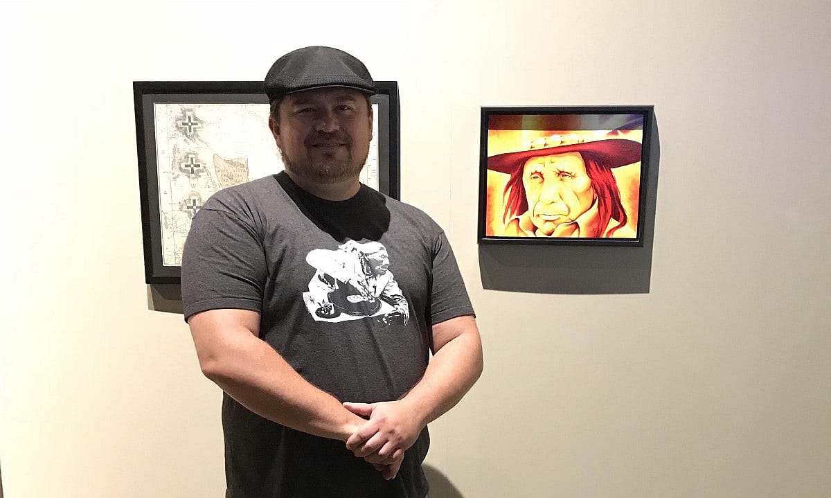 Robert Martinez stands in front of one his artworks displayed in Native Nations Now: An Exhibition of Contemporary Native Art at the Plains Indian Museum