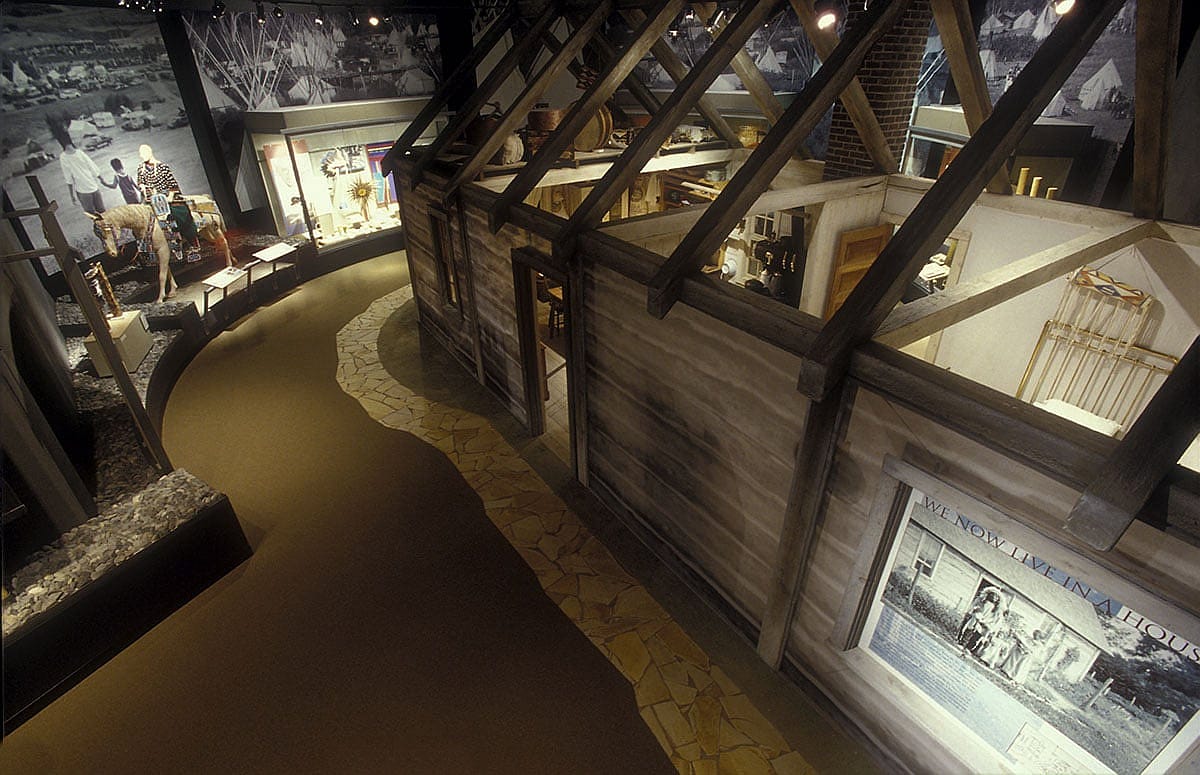 The centerpiece of the Plains Indian Museum's Adversity and Renewal gallery is a reproduction of the 1911 log house that belonged to Standing Bear, Oglala Lakota, in the Wounded Knee District of Pine Ridge, South Dakota. Arthur Amiotte, Lakota artist and scholar, guided the recreation of his great-grandfather's home. His voice and that of Gloria Goggles, Lakota, interpret the house's nurturing environment - full of innovation and tradition - that teaches important lessons to future generations.