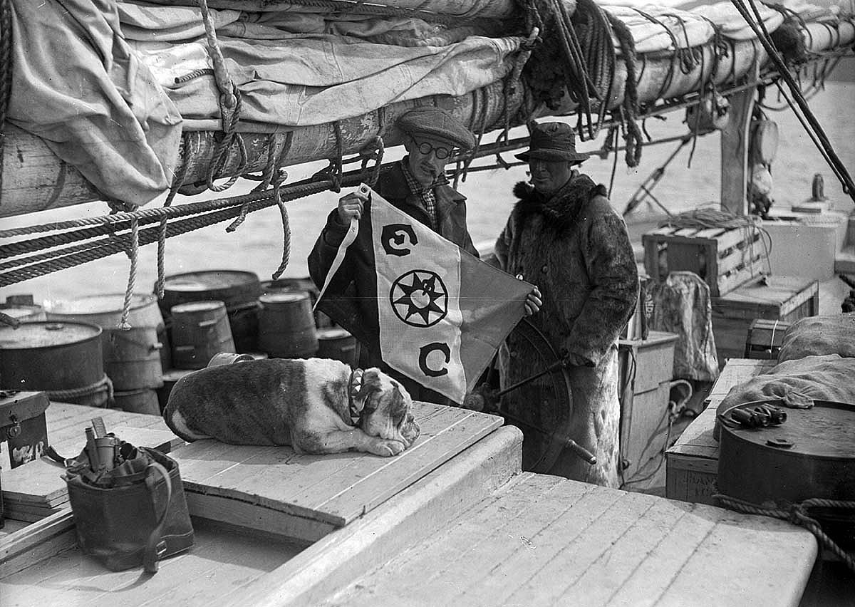 Harold McCracken and Robert Bartlett with the Explorers Club flag while Toughy the bulldog keeps a sleepy watch. MS 305 Harold McCracken Photograph Collection, McCracken Research Library. N203#A1026V
