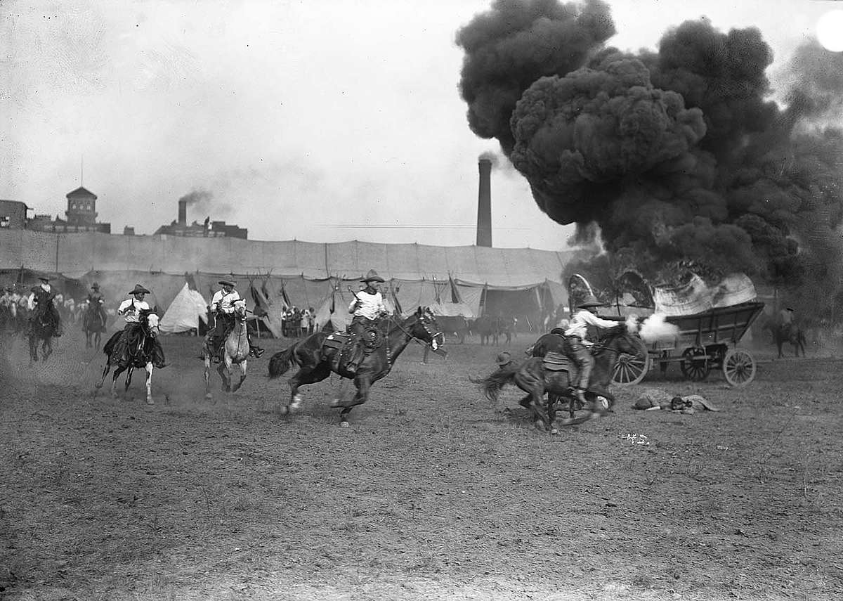 Cowboys circling burning covered wagon in the Wild West Show arena. MS 47 David R. Phillips Collection, McCracken Research Library. PN.47.11
