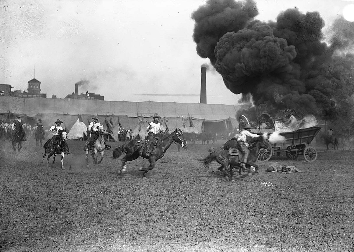 Cowboys circling burning covered wagon in the Wild West Show arena. MS 47 David R. Phillips Collection, McCracken Research Library. PN.47.11
