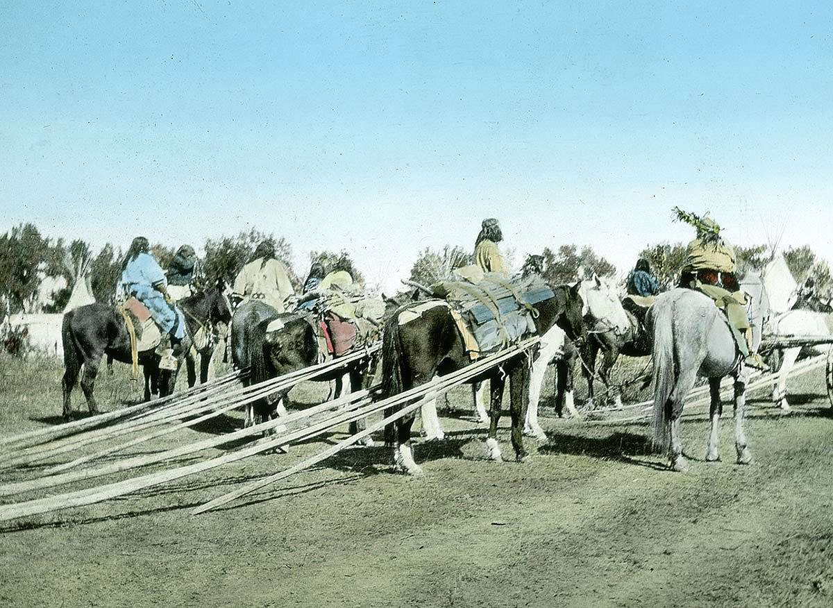 Several Crow people on horseback dragging tipi poles, ca. 1903-1925. MS 95 William A. Petzoldt Lantern Slide Collection. LS.95.294
