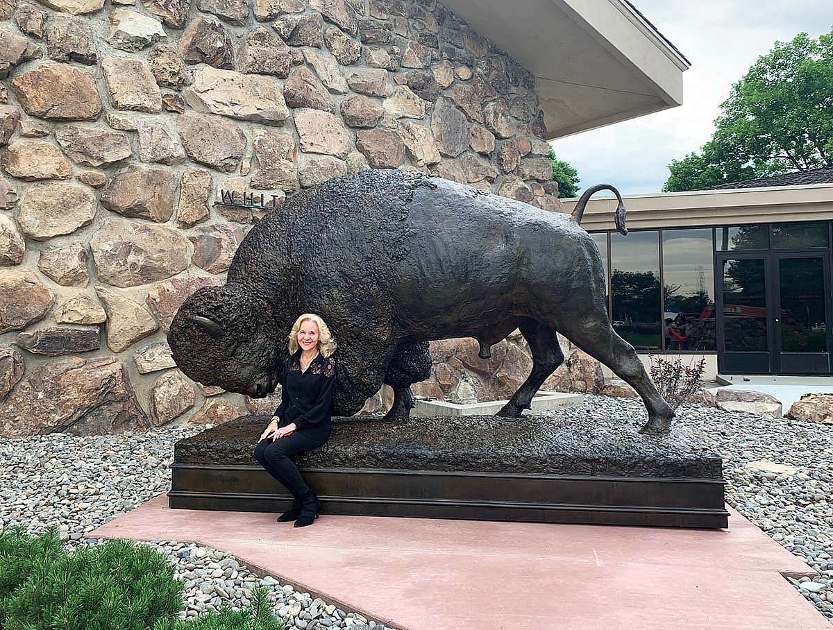 Naoma Tate, Center of the West Trustee and donor of Distant Thunder, poses with the sculpture after its successful installation.