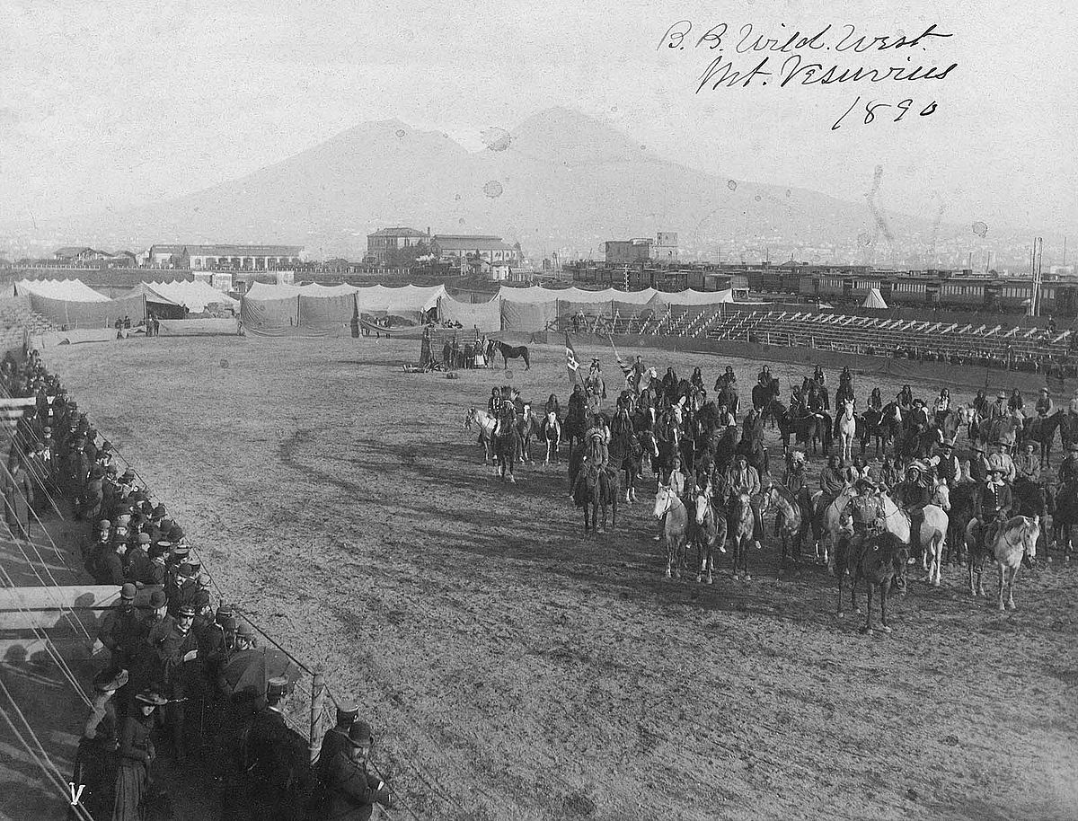 William F. Cody at the front of a group of cowboys and Native American men mounted on horses in Wild West show arena, 1890. Mount Vesuvius, Italy, appears in the background. MS 6 William F. Cody Collection, McCracken Research Library. P.69.0806