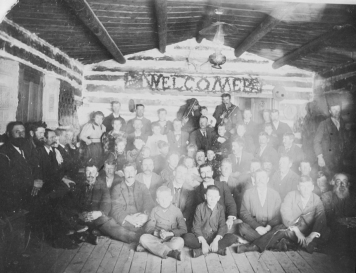 This group of people gathered under a "Welcome" sign in a log building in Wyoming in the early 1900s. We don’t know their names, or where the building stood. F.J. Hiscock photograph. MS89 Jack Richard Photograph Collection, McCracken Research Library. PN.89.18.3085.36