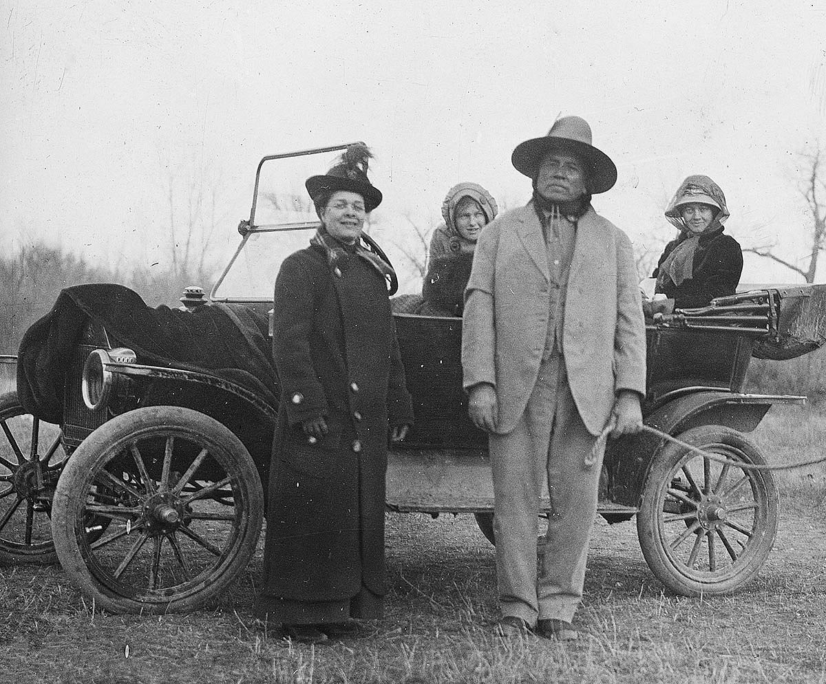 Miss Crawford, missionary to Kiowas, with Curley (Custer Scout); Anna and Genevieve Petzoldt in car, Montana, ca. 1903-1925. MS 95 William A. Petzoldt Lantern Slide Collecction. LS.95.143