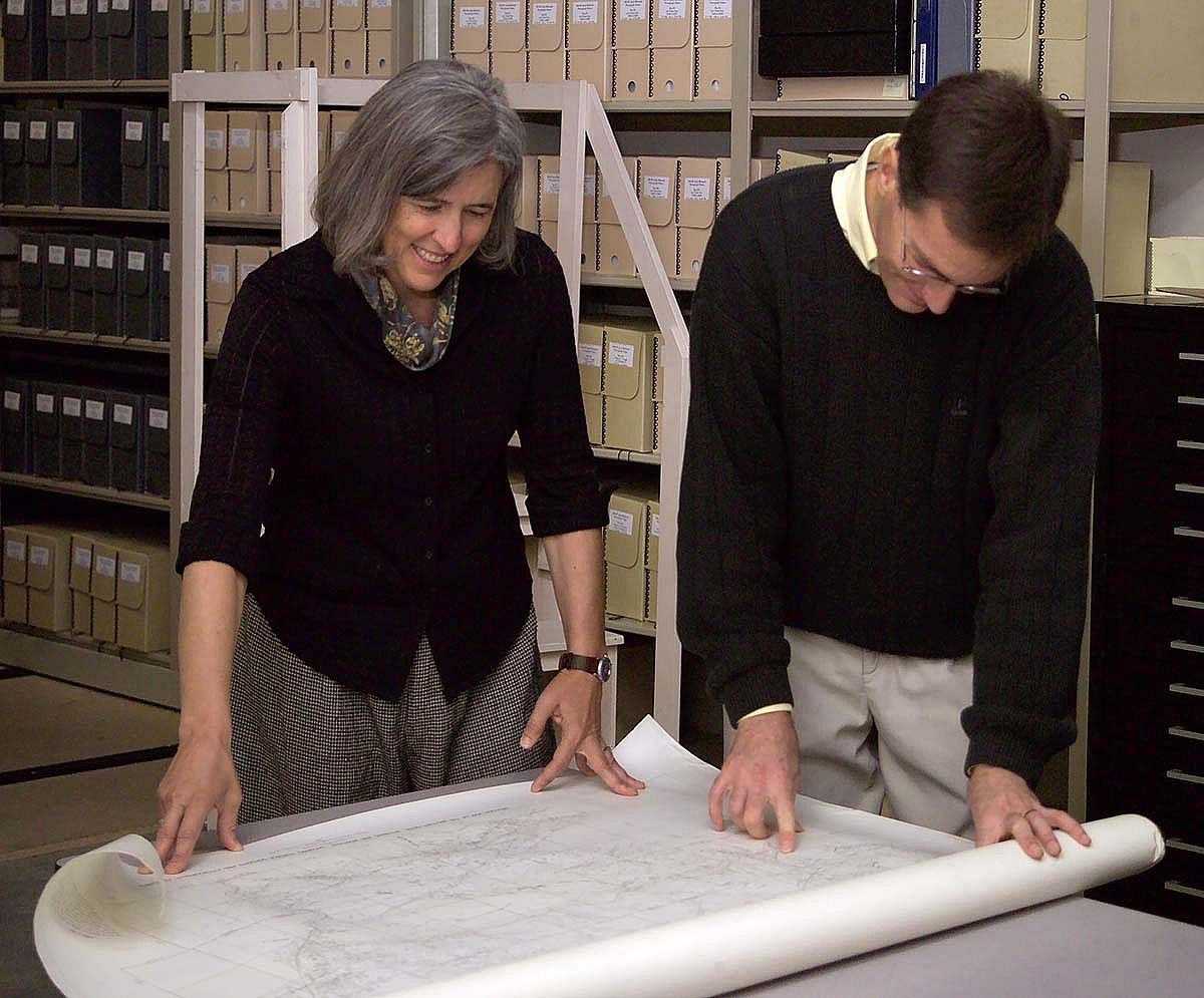 Librarian [now Library Director] Mary Robinson and [former] Cody Institute for Western American Studies Co-Director Kurt Graham examine historic maps in one of the McCracken Research Library vaults.