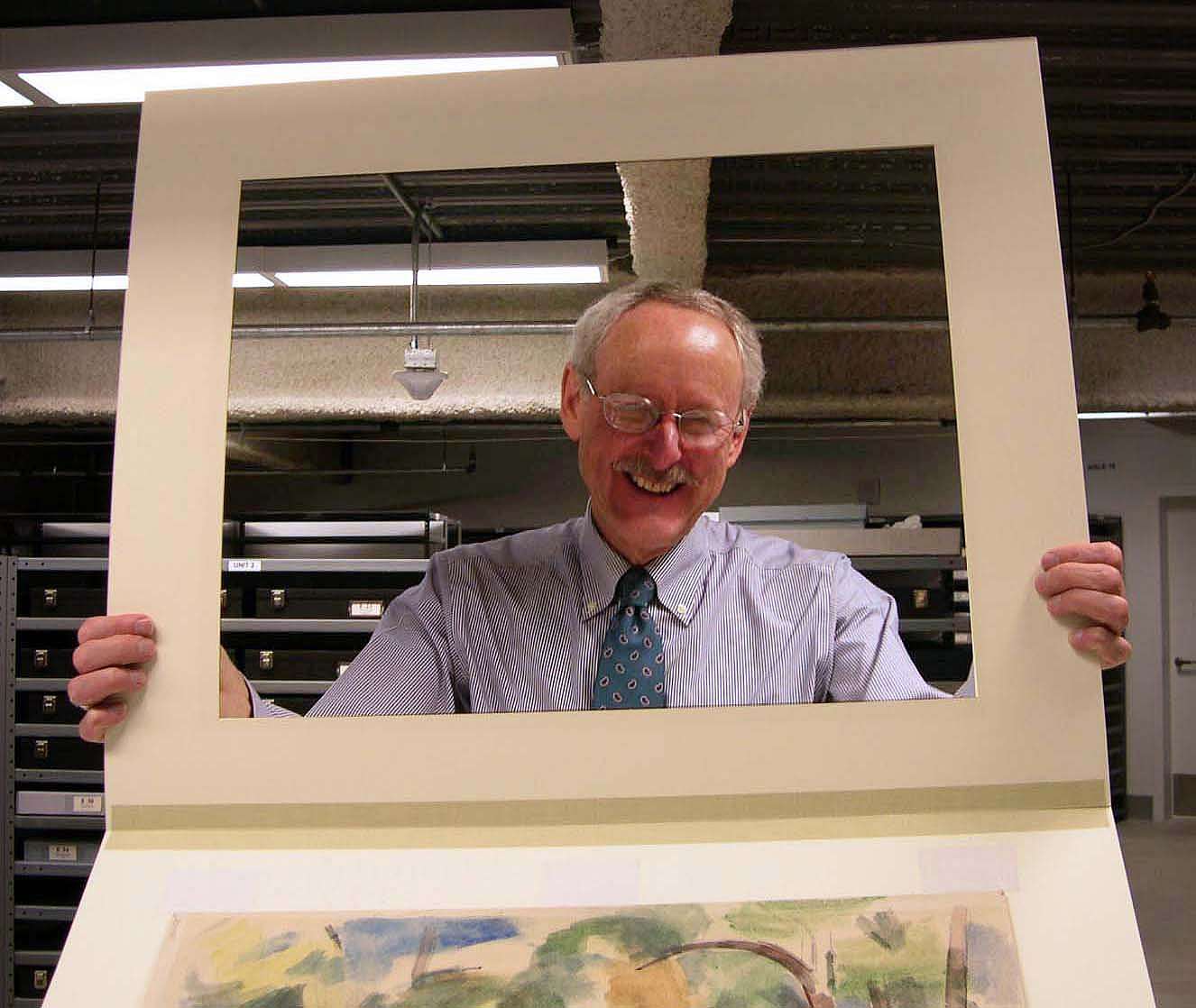 Peter Hassrick looking through the frame created by a picture mat.