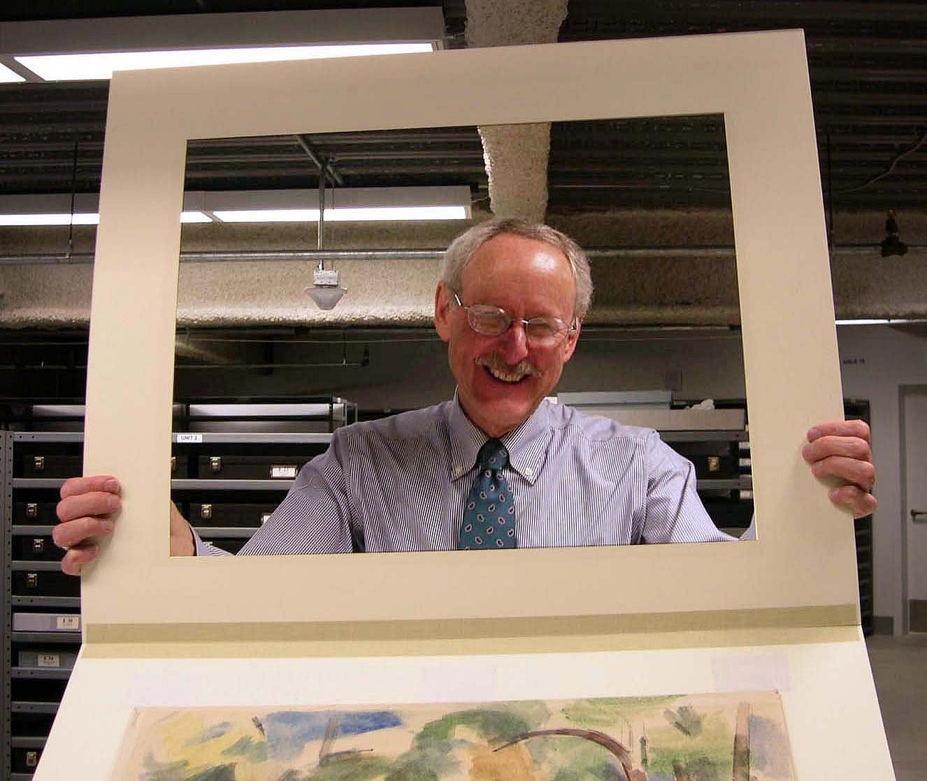 Peter Hassrick looking through the frame created by a picture mat.