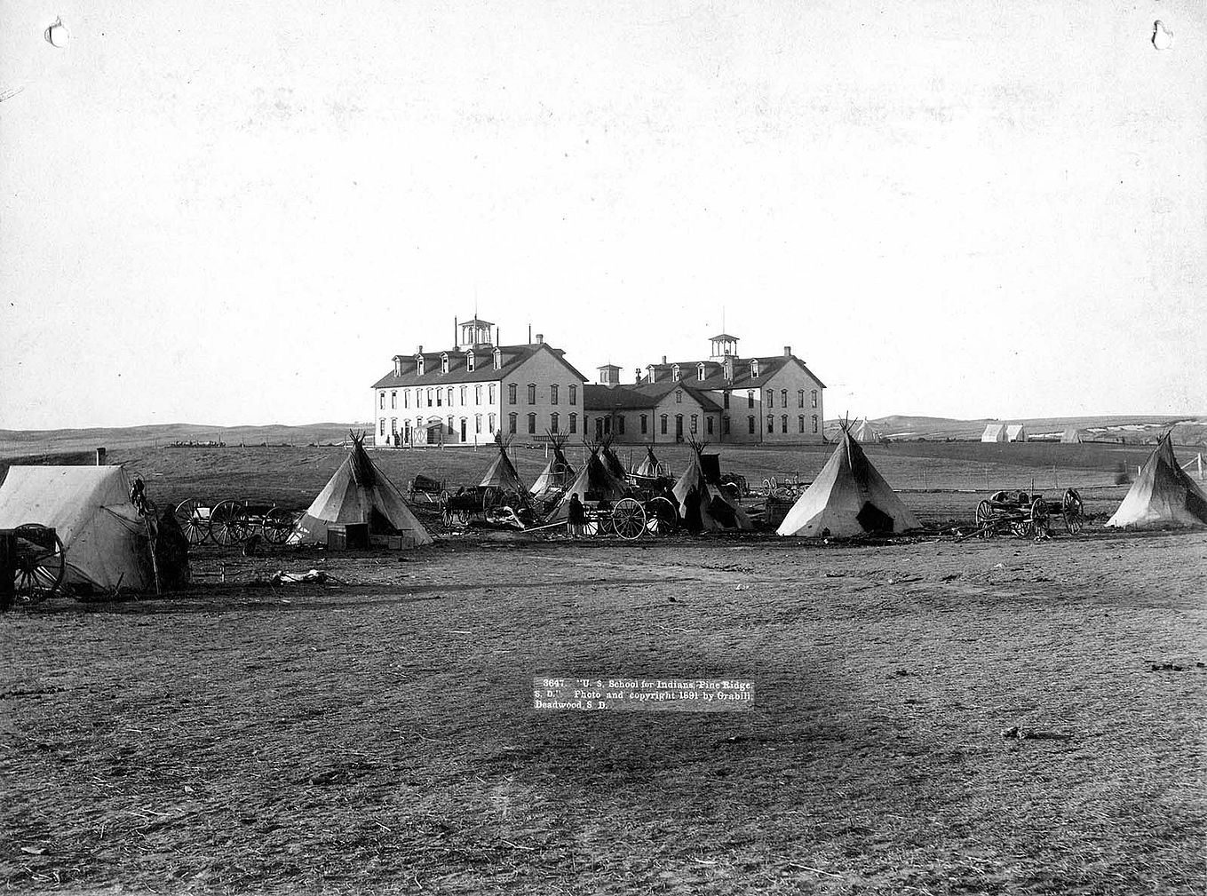 “U.S. School of Indians at Pine Ridge, 1891.” John C.H. Grabill was an early and active photographer in South Dakota. This print captures the stark contrast between the traditional ways of the Native Americans and the new social order. MS 35 Richard Pohrt Collection. P.35.17.2