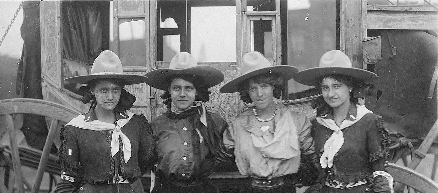 Four cowgirls posing in front of a stagecoach for the 101 Ranch Show, ca. 1916. Sepia toned photograph. MS 6 William F. Cody Collection, McCracken Research Library. P.69.1289 (detail)