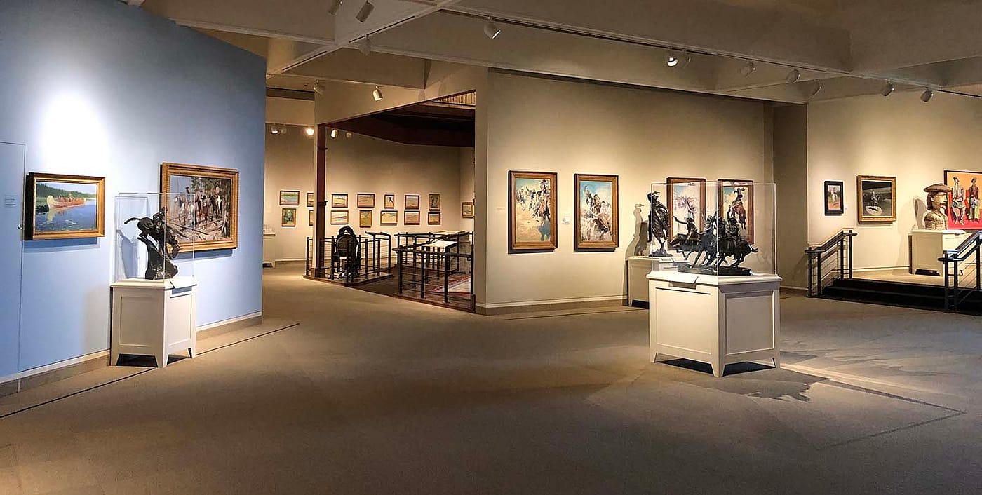 Interior of the Whitney Western Art Museum, showcasing a variety of Western art pieces, including paintings and sculptures, in a well-lit gallery setting.