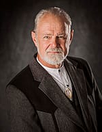 Formal portrait of Bob Berry in gray and black jacket, on gray background.
