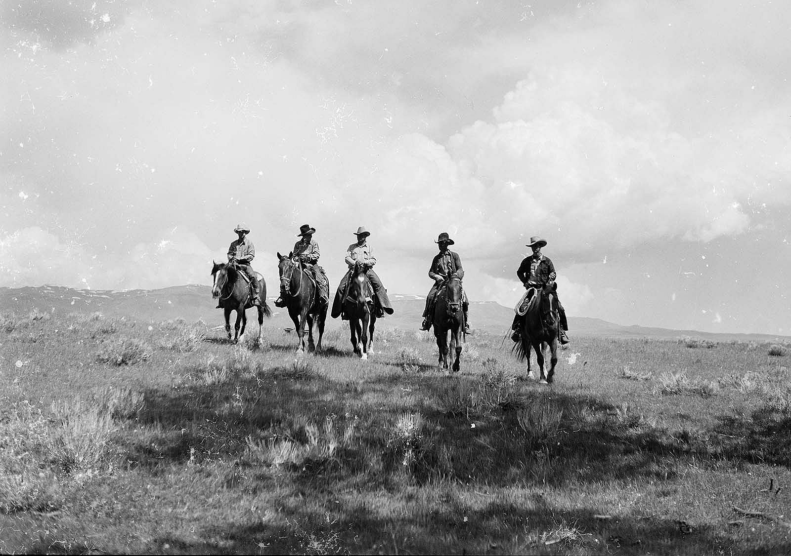 Black & white photograph of five cowboys riding horses on the range. PN.67.049