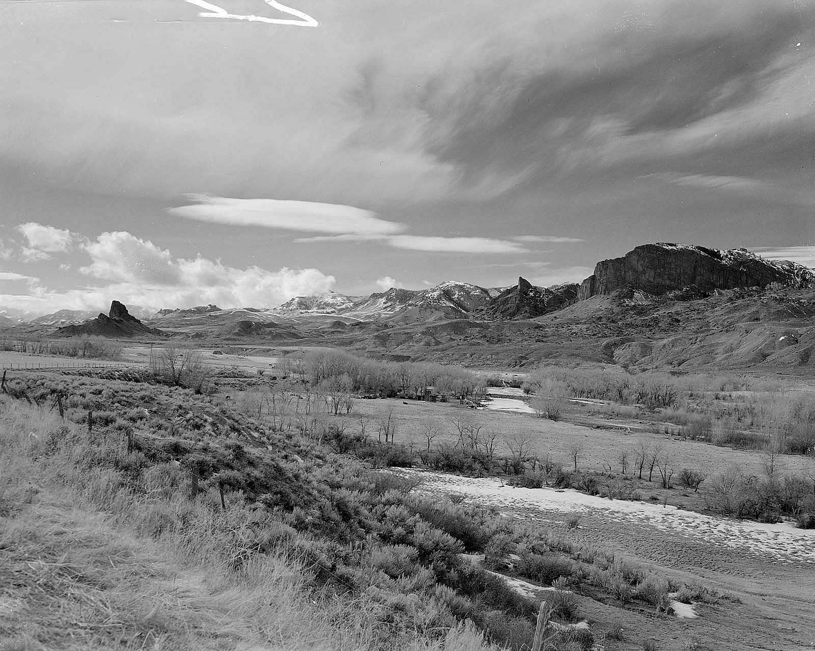 With the Absaroka Mountains in the background, Castle Rock stands in the South Fork Valley. The formation was originally named Ishawooa by the Shoshone Indians. From here, Jones and his party crossed the Absarokas to the North Fork of the Shoshone River on the other side. MS 089 Jack Richard Photograph Collection, McCracken Research Library. PN.89.114.21370.9