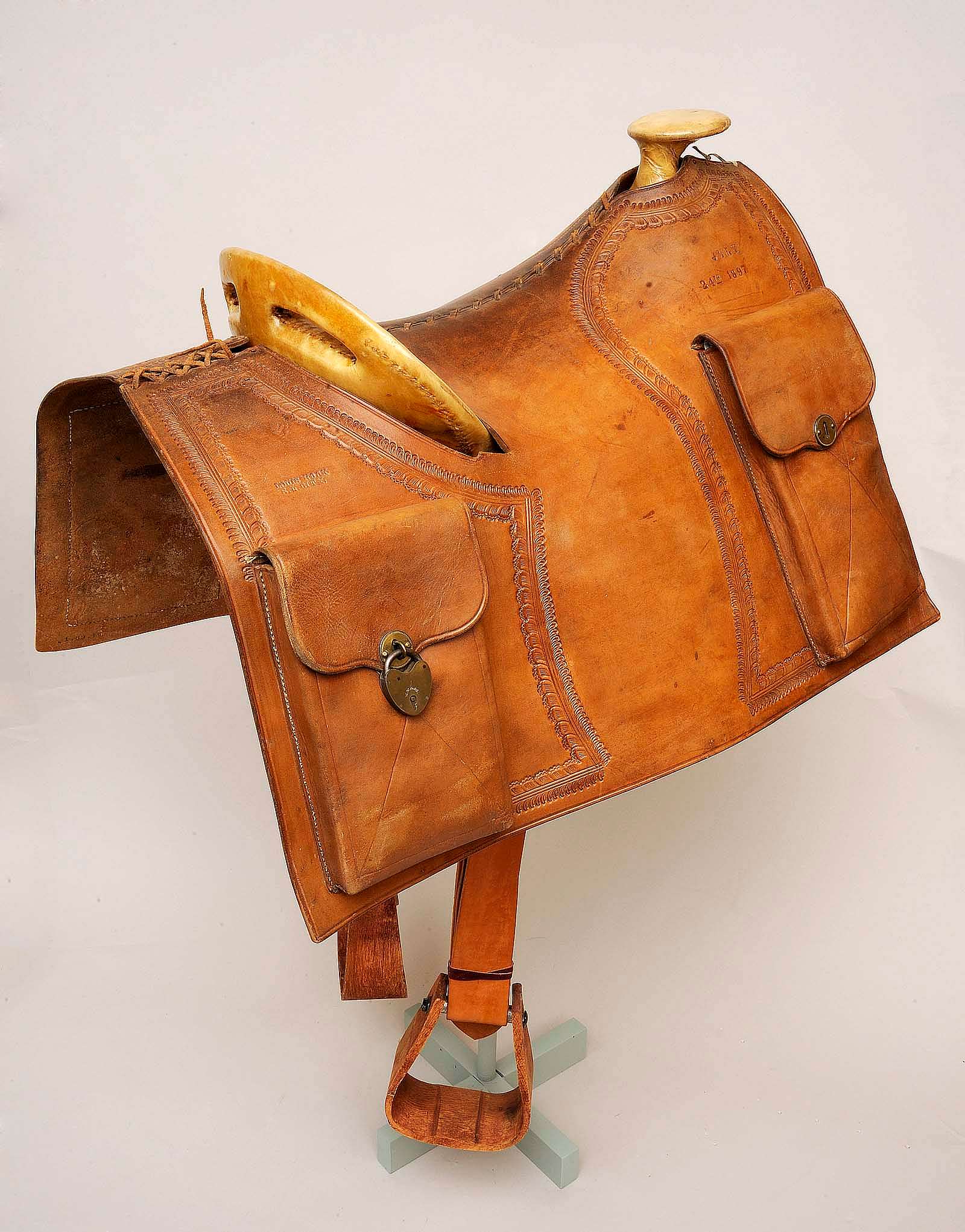 Pony Express style saddle with mochilla. Stamped left side front: PONY EXPRESS/MARCH 3RD 1860, Stamped left side back: LOUIS HOOK/S.L. CITY, Stamped right side front: JULY/24TH 1897, Stamped right side back: LOUIS HOOK/S.L. CITY. This is a reproduction possibly used in Wild West Show performances. Date: March 3, 1860; July 24, 1897. Museum purchase, Garlow Collection. 1.69.16