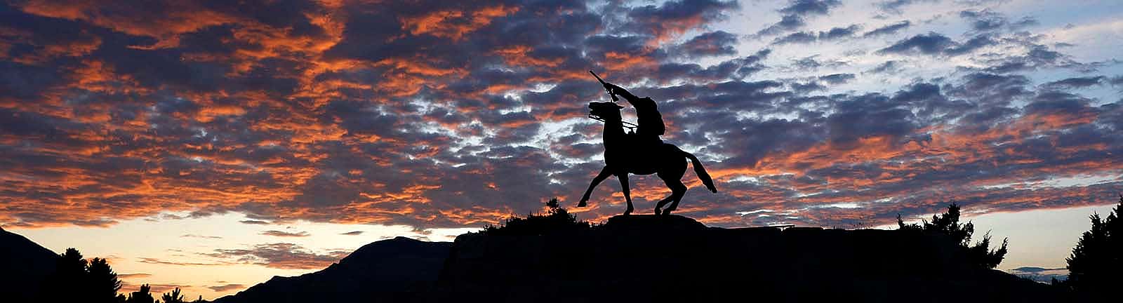 “Buffalo Bill—The Scout” sculpture by Gertrude Vanderbilt Whitney, silhouetted against a sunset sky. 3.58