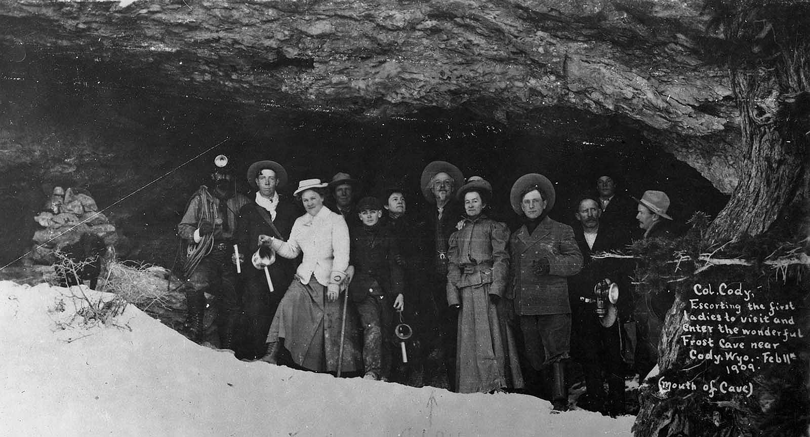 Black & white photo of William F. Cody with a group at the mouth of Frost Cave, which was later renamed Spirit Mountain Cavern, on Cedar Mountain, 1909. MS 434 Harry Miller Shoshone National Forest Ranger Collection, McCracken Research Library. MS434.01.01.041