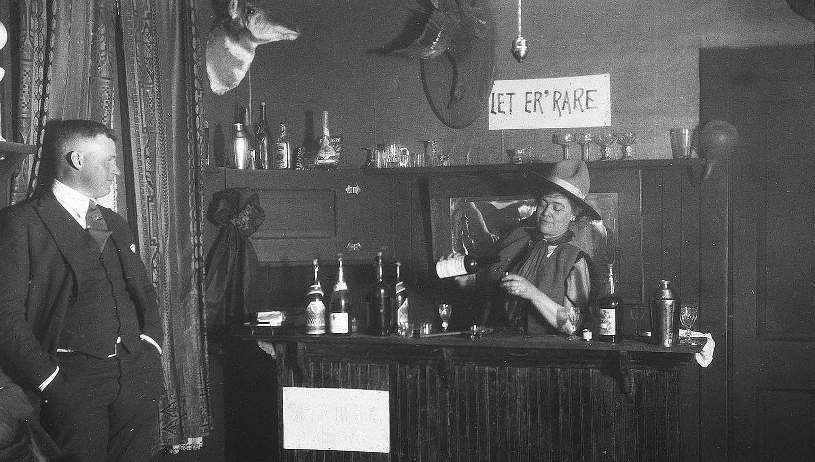 Caroline Lockhart pours a drink at a bar while a man looks on. MS 6 William F. Cody Collection. P.69.1761