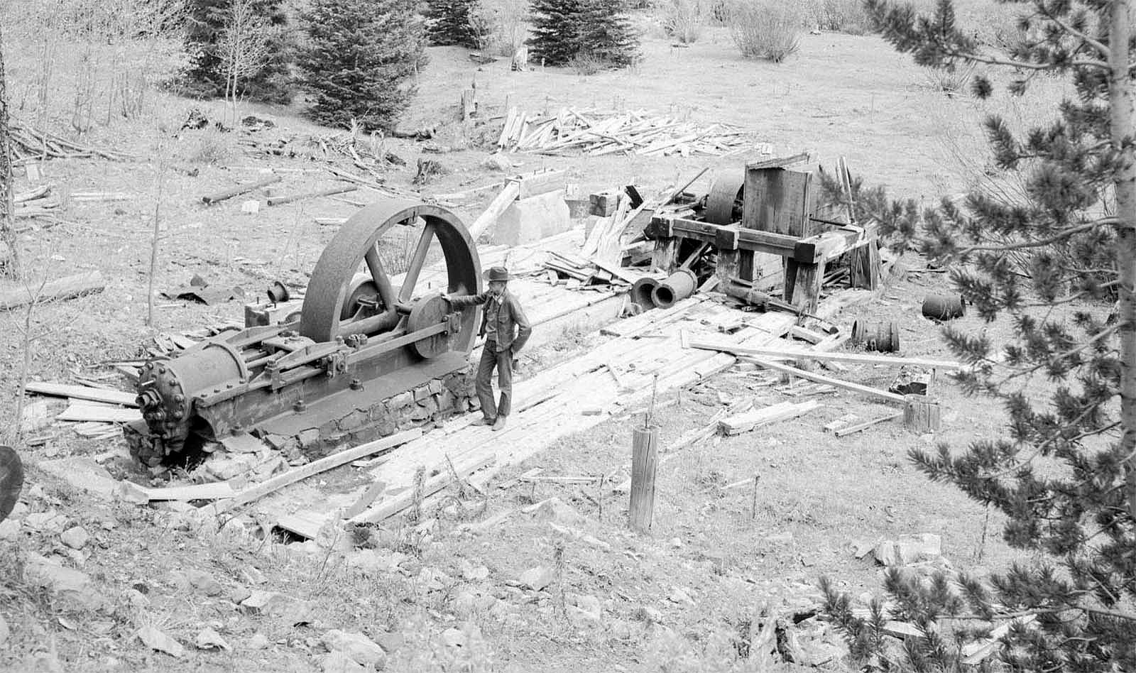 Black & white photograph of Jim Dunrud standing next to power plant for electricity at Kirwin, Wyoming. PN.89.112.21271.9