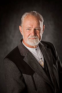 Formal portrait of Bob Berry in gray and black jacket, on gray background.