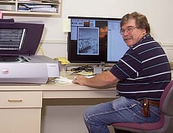 Mack Frost with the tools of the trade: a scanner and computer.