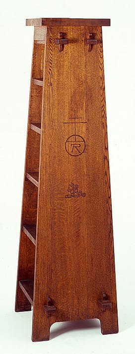 Sharp's oak Roycroft magazine pedestal, ca. 1905. Visible joints on the side show how the piece was constructed. Such "revealed design" elements are a common characteristic of Arts and Crafts furniture. The pedestal also bears the Roycroft mark, an orb and cross. Height 64 inches. 19.00.79