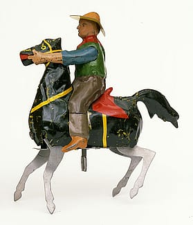 A toy cowboy on a windowsill, part and parcel of a youngster's dreams of the West. "The Bucking Broncho," ca. 1932. The likeness of Buffalo Bill in a tin toy. Gift of Christopher and Rene Turner. 1.69.6014.1