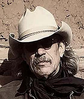 Headshot of Jim Arndt in light-colored, small brimmed cowboy hat with a dark bandana.