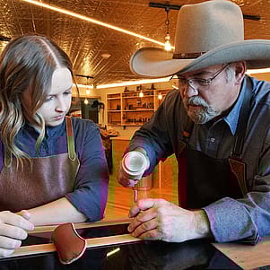 Scout Saddle Company master Keith Seidel (right) teaches leatherworking skills to apprentice Kali Shatto