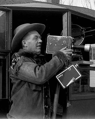 Ned Frost with movie cameras, standing in the door of his home-built RV and photography platform.
