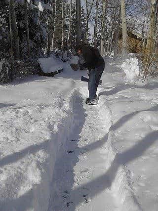 Man shoveling snow off the sidewalk.