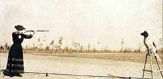 Annie Oakley plans to shoot an apple off the head of her dog Dave in this postcard image. P.94.1